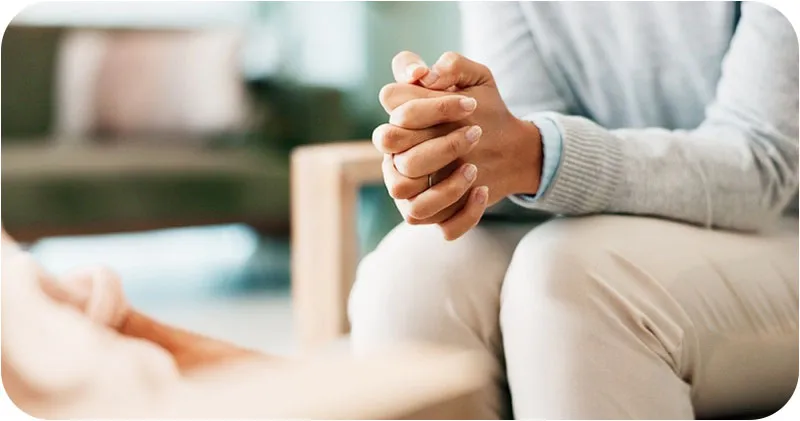 a person sitting in a chair with intertwined hands